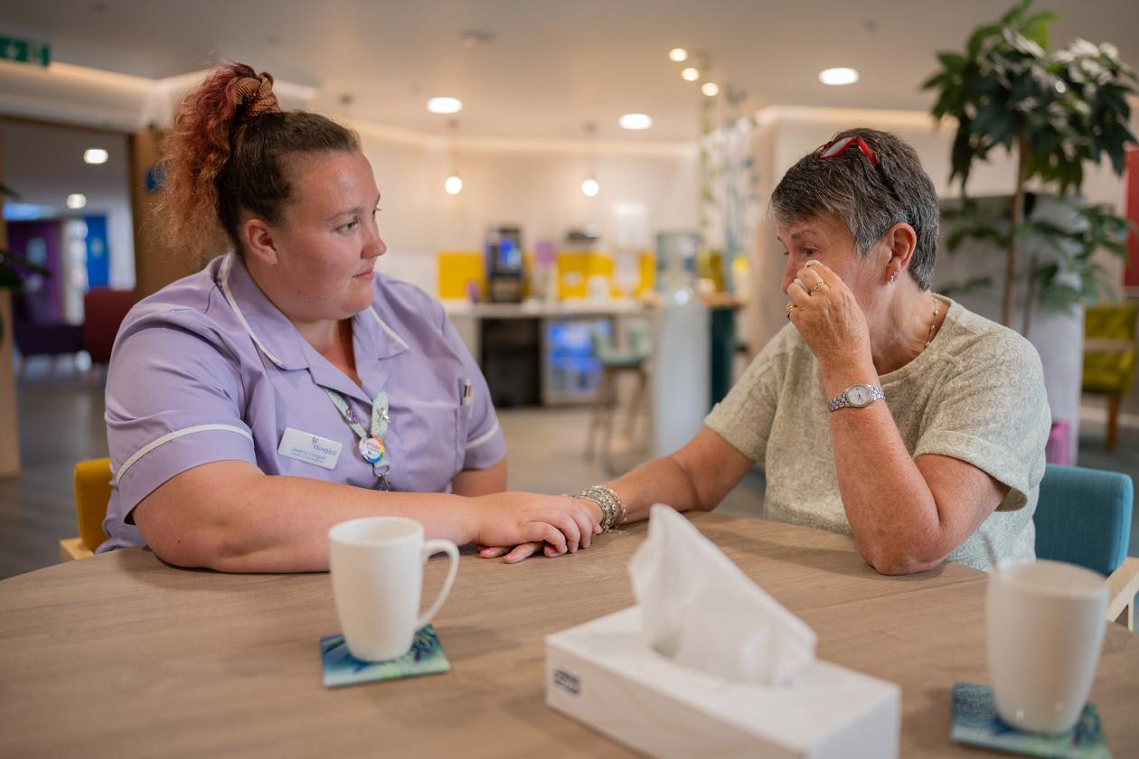 A nurse holds a hand of a patient who is upset
